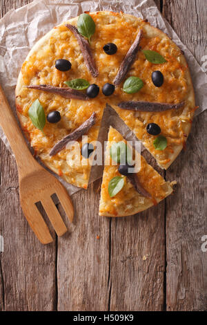 In Scheiben geschnitten Pizza mit Sardellen und Zwiebeln auf dem Tisch. vertikale Ansicht von oben Stockfoto