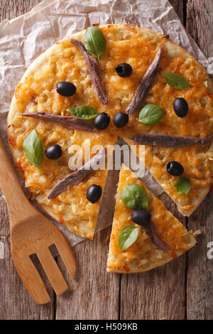 In Scheiben geschnittene Pizza mit Sardellen und Zwiebeln Nahaufnahme auf dem Tisch. vertikale Ansicht von oben Stockfoto