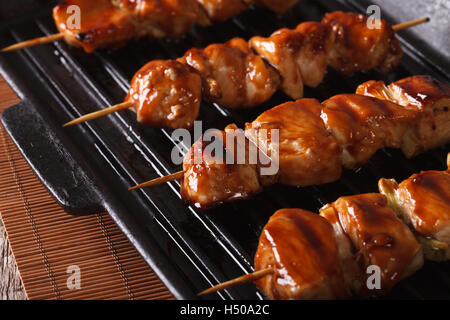 Japanische Yakitori Spieße mit Hähnchen auf einer Grillpfanne. Horizontale Nahaufnahme Stockfoto