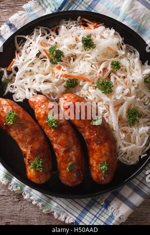 gegrillte Würstchen und Sauerkraut auf einem Teller mit einer Tabelle Großaufnahme. vertikale Ansicht von oben Stockfoto