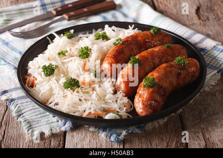 Deutsche Bratwurst und Sauerkraut auf einem Teller auf den Tisch. horizontale Stockfoto