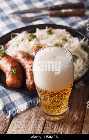 Lager-Bier mit Schaum und Sauerkraut mit Wurst auf den Tisch-Nahaufnahme. Vertikal Stockfoto