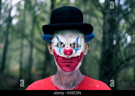 Nahaufnahme eines unheimlich böse Clowns einen Bowler-Hut im Wald Stockfoto
