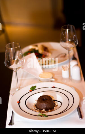 Es ist ein romantisches Abendessen zu zweit. Ein Soufflé ist wunderschön auf einem Tisch im stilvollen Restaurant mit Wein Gläser serviert. Stockfoto