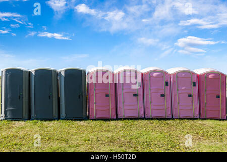 Grau und rosa Kunststoff Mobiltoiletten auf ein offenes Feld für ein outdoor-Event. Stockfoto