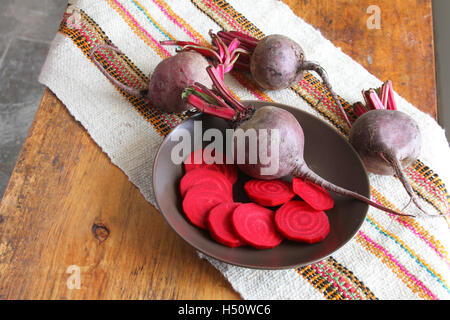 Schüssel mit ganze und geschnittene Rüben auf einem Tisch mit bunten Tischset in Peru Stockfoto
