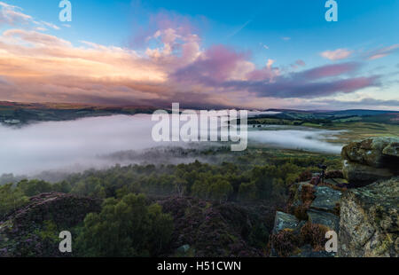 Bunte Sonnenaufgang Wolken über Tal im Nebel mit Fotografie Kamera am Rande der Felsen bedeckt Stockfoto