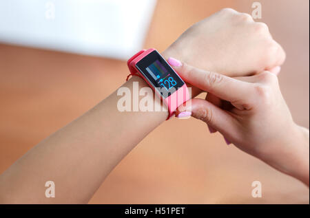 Isolierten weiblichen Hand mit rosa Smartwatch Puls nach dem Training indoor auf Licht und erlauben Hintergrund Stockfoto