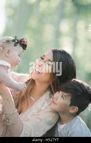 Porträt von einem lächelnden Baby, Mutter und junge Mädchen mit einem Blumen-Kranz auf dem Kopf. Stockfoto