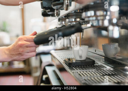 Nahaufnahme eines Mannes vor Espresso-Maschine, frischen Espresso in eine Tasse laufen. Stockfoto