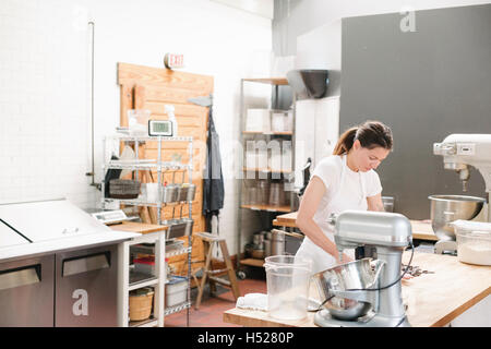 Frau trägt eine weiße Schürze an einem Schalter der Arbeit in einer Bäckerei. Stockfoto
