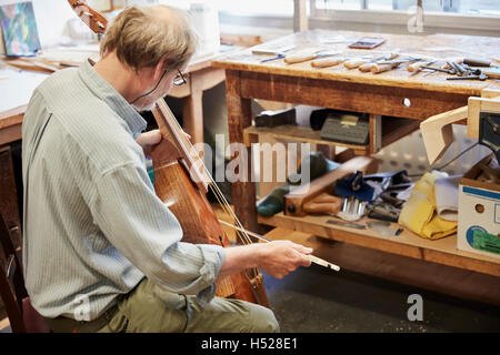 Ein Geigenbauer in seiner Werkstatt spielen Instrument mit einer Verbeugung, tuning und Veredelung. Stockfoto