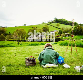 Eine Künstlerin arbeiten im Freien in der Landschaft sitzt auf dem Boden wieder anzeigen. Stockfoto