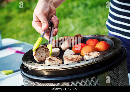 Frau, englisches Frühstück auf einem Campingkocher vorbereiten. Stockfoto