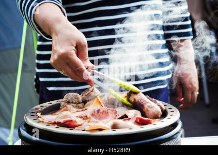 Frau, englisches Frühstück auf einem Campingkocher vorbereiten. Stockfoto