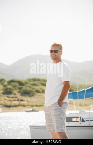 Blonder Mann mit Sonnenbrille auf einem Steg. Stockfoto
