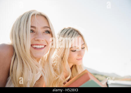 Zwei blonde Schwestern liegen auf einem Steg, ein Buch zu lesen. Stockfoto
