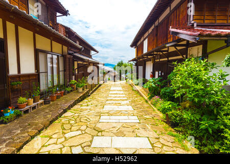 Wunderschön restaurierte traditionelle Holzhäuser Linie die Seiten von einem Stein Weg auf der alten Nakasendo Poststraße tagsüber trail Stockfoto