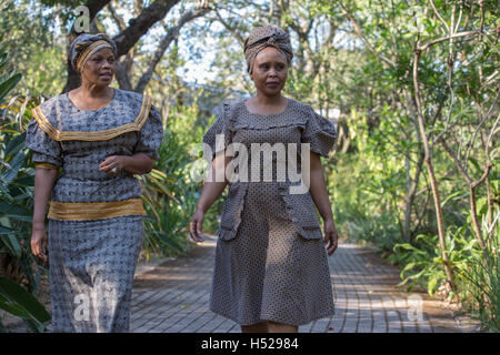 Zwei afrikanische Frauen in traditionellen Seshweshwe zu kleiden, zu Fuß in ein Garten Stockfoto