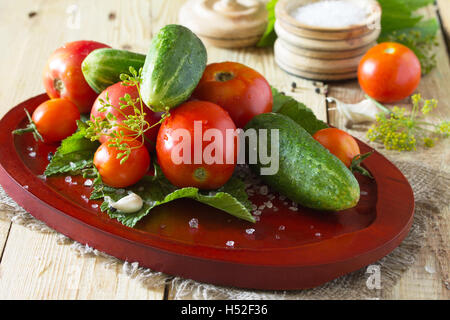 Erhaltung der frische und eingelegte Gurken und Tomaten, Gewürze und Knoblauch auf einem Holztisch. Haus Gemüsekonserven. Stockfoto