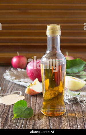 Apfelessig in eine Glasflasche mit frischen Äpfeln auf einem Holztisch. Platz für Ihren Text zu kopieren. Stockfoto