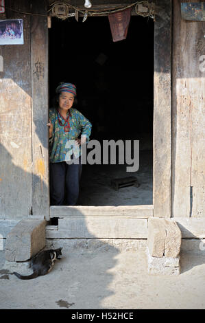 Hmong Frau und Katze an der Tür eines traditionellen Hauses in der Provinz Ha Giang, Nord-Vietnam Stockfoto