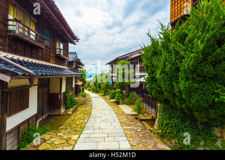 Restaurierten steinernen Fußweg auf alten Nakasendo Wanderweg dicht gesäumt von traditionellen Holzhäuser unter bewölkten Tag blickte Stockfoto