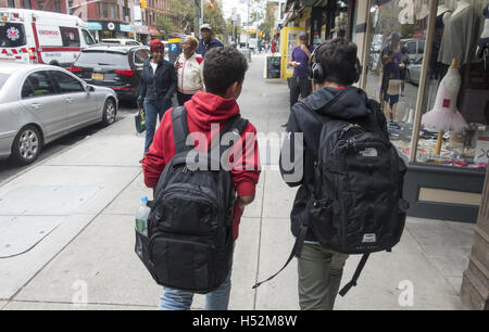 Zwei Freunde mit Rucksäcken voller Bücher gehen Sie 7th Avenue in Park Slope, Brooklyn auf ihrem Weg zur Schule am Morgen. Stockfoto