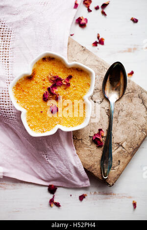 Hausgemachte Crème brûlée mit Edble rosa Rosen Stockfoto