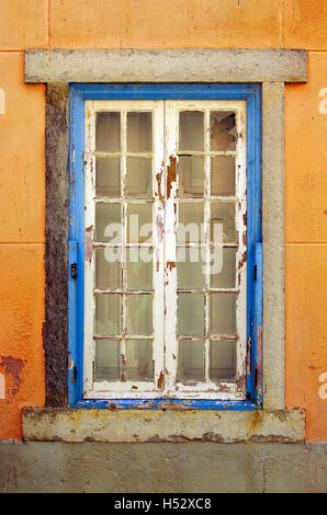 Alten und beschädigten Fenster mit blauen Rahmen in verlassenen gelbe Haus Stockfoto