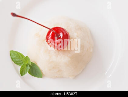 Luft-weiße Mousse-Dessert mit Kirschen und Minze auf einem weißem Hintergrund Draufsicht verziert. Stockfoto