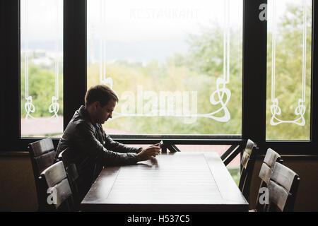 Junger Mann sitzen in der Stadt-Café während der Mittagszeit und am tablet Stockfoto