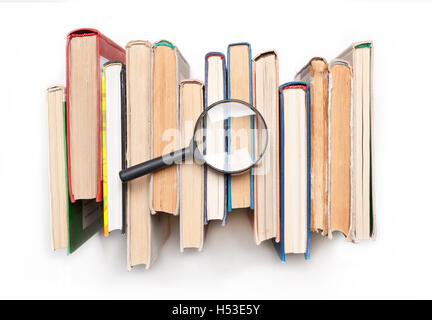 Stapel von gebundene Bücher mit Lupe isilated auf weißem Hintergrund, Ansicht von oben. Suche nach relevanten und erforderlichen Informat Stockfoto
