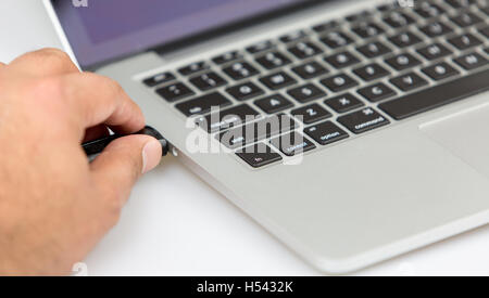 Eine männliche Person, die einen Laptop USB-Datenstick Reisenden einstecken. Nahaufnahme von linken Seite gedreht Stockfoto