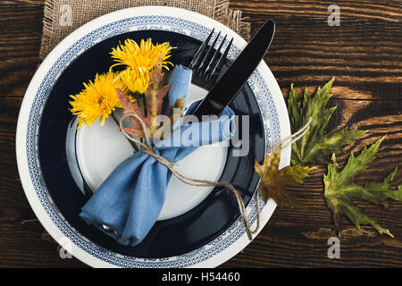 Rustikale Herbst Gedeck mit gelben Blüten auf rustikalen Holztisch, Draufsicht, Thanksgiving Dekorationen mit Textfreiraum Stockfoto