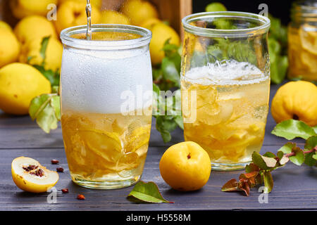 kohlensäurehaltige Getränke mit Sirup aus japanische Quitte auf frisches Obst Hintergrund Stockfoto