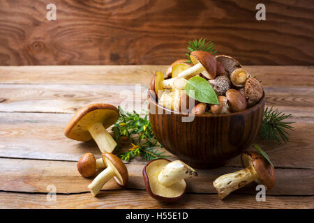 Essbare Pilze in der Holzschale. Frische Wald Pilze auf dem rustikalen Tisch. Stockfoto