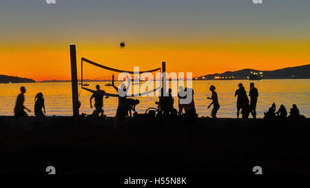 Volley-Ball-Teams spielen in der Silhouette gegen Sonnenuntergang am Strand. Stockfoto