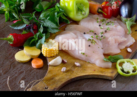 Frisches rohes Hühnchen mit Gemüse auf ein Schneidebrett. Stockfoto