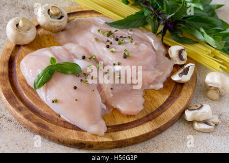 Rohem Hühnerfleisch mit Nudeln Spaghetti und Pilzen auf braunen Stein Hintergrund. Stockfoto