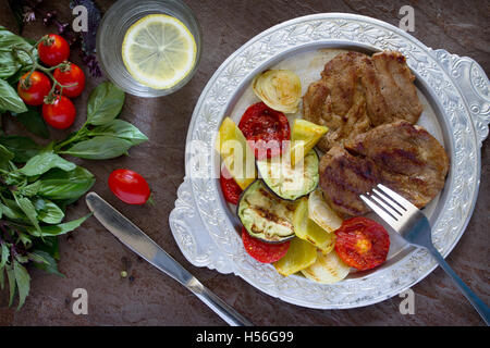 Gegrilltes Steak Fleisch Schweinefleisch und Grillgemüse auf braunen Stein Hintergrund. Ansicht von oben. Stockfoto