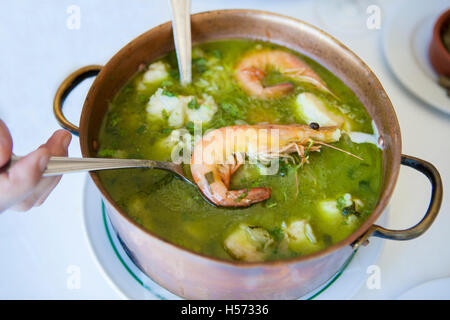 Arroz de Tamboril oder suppenartige Meeresfrüchte Reis, portugiesischen Rezept. Hand hält den Löffel mit einer Garnele Stockfoto