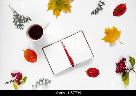 Arbeitsbereich. Flache Zusammensetzung des geöffneten Notizbuch, Stift, eine Tasse Tee, Herbstlaub, Ahornblatt, roten Beeren der Eberesche auf weißem Hintergrund Stockfoto