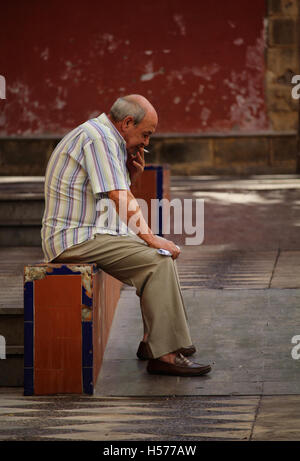 JEREZ DE LA FRONTERA/Spanien - 6. Oktober 2016: Senior Mann saß und rauchte eine Zigarette in der Altstadt von Jerez De La Frontera, and Stockfoto