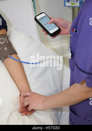 Krankenschwester Einnahme eine Patienten-Blutdruckmessung über eine mobile App. Stockfoto