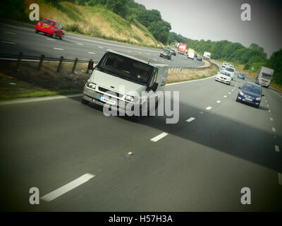 Weißer Lieferwagen und andere Fahrzeuge fahren mit Geschwindigkeit auf einer Autobahn im Vereinigten Königreich. Stockfoto