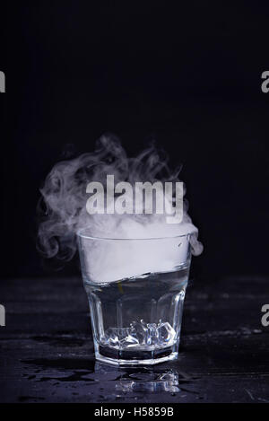 Heißes Wasser mit viel Dampf in einem Glas auf einem schwarzen Hintergrund. Dunkles Foto. Konzept-Foto: drei Stand der Wasser - Eis, Wasser, St Stockfoto