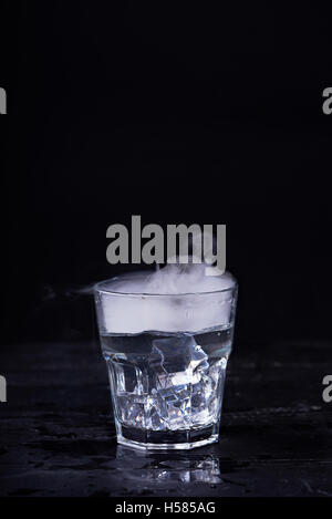 Heißes Wasser mit viel Dampf in einem Glas auf einem schwarzen Hintergrund. Dunkles Foto. Konzept-Foto: drei Stand der Wasser - Eis, Wasser, St Stockfoto