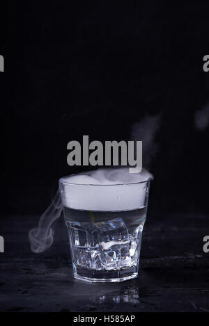 Heißes Wasser mit viel Dampf in einem Glas auf einem schwarzen Hintergrund. Dunkles Foto. Konzept-Foto: drei Stand der Wasser - Eis, Wasser, St Stockfoto