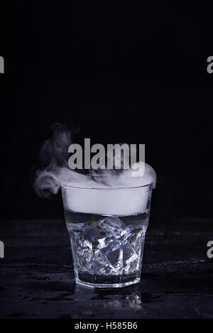 Heißes Wasser mit viel Dampf in einem Glas auf einem schwarzen Hintergrund. Dunkles Foto. Konzept-Foto: drei Stand der Wasser - Eis, Wasser, St Stockfoto